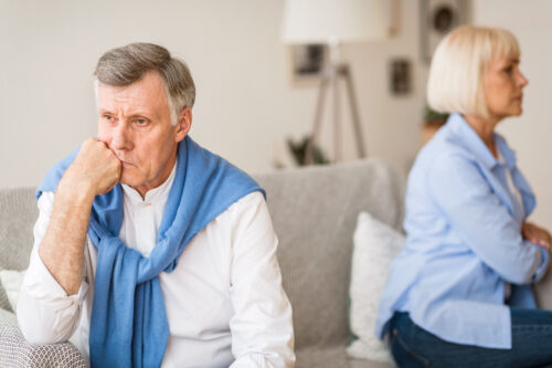 older couple gray divorce sitting on couch facing opposite of each other